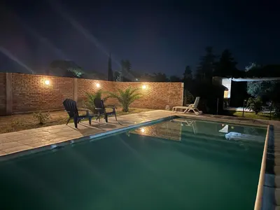 a swimming pool at night with two chairs next to it at Julias House in Almafuerte