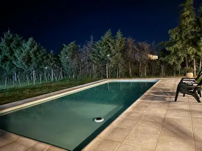 a swimming pool at night with two chairs next to it at Julias House in Almafuerte