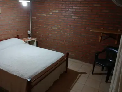 a bedroom with a bed and a brick wall at Los Nidos Dormis Habitaciones con baño privado y DEPARTAMENTOS in Villa Cura Brochero