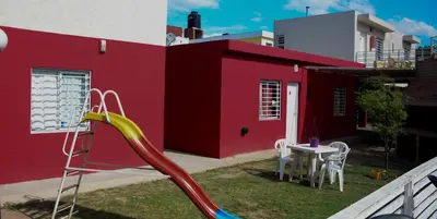 a red house with a slide in the yard at Cerros de la Villa in Villa Carlos Paz