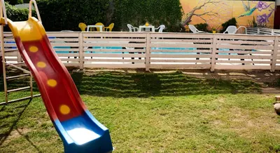 a red and blue slide in a yard with a fence at Cerros de la Villa in Villa Carlos Paz
