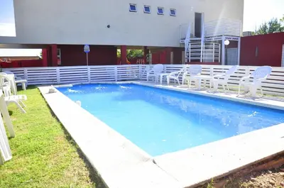 a large swimming pool with white chairs in a yard at Cerros de la Villa in Villa Carlos Paz