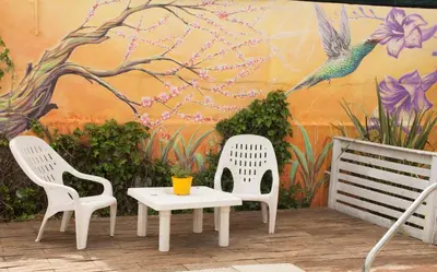 two chairs and a table in front of a mural at Cerros de la Villa in Villa Carlos Paz