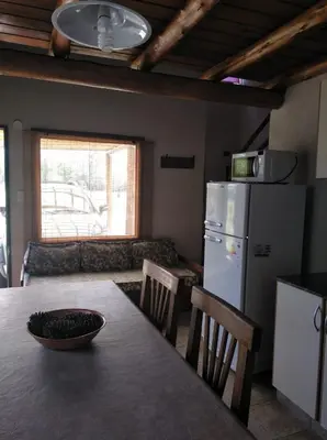 a kitchen with a table and a refrigerator and a couch at Cabañas el Ñato in Nono