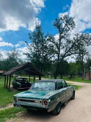 an old green car parked on a dirt road at Complejo Las Sierras in Nono