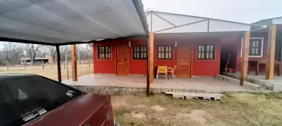 a red house with a porch and a car parked at AYRES DE MONTAÑA in San Ignacio