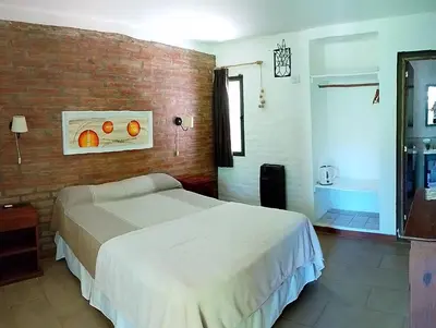 a bedroom with a bed and a brick wall at Portal del Río Posada in Santa Rosa de Calamuchita