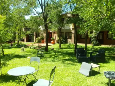a group of chairs and a table in the grass at Portal del Río Posada in Santa Rosa de Calamuchita