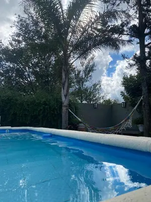 a swimming pool with a palm tree and a fence at TANTI casa con pileta in Cordoba