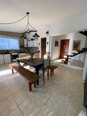 a kitchen and dining room with a table and benches at TANTI casa con pileta in Cordoba