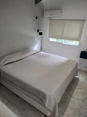 a white bedroom with a bed and a window at Departamento W R T 2 in Villa Carlos Paz