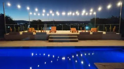 a patio with chairs and a pool at night at Cabañas Nakupenda in Villa Carlos Paz