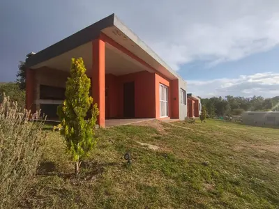 a small red building on a grass field at Cabañas Nakupenda in Villa Carlos Paz