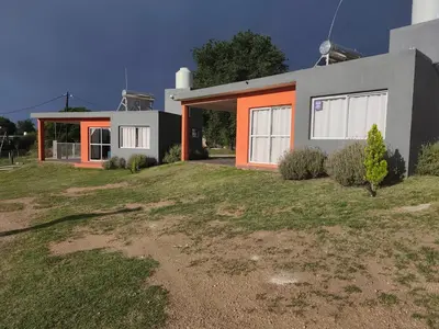 a house with an orange door on top of a yard at Cabañas Nakupenda in Villa Carlos Paz