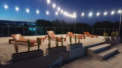 a group of chairs and benches on a patio at night at Cabañas Nakupenda in Villa Carlos Paz