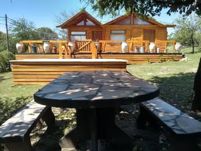 a picnic table in front of a log cabin at Talasuas -aires de montaña in Villa General Belgrano