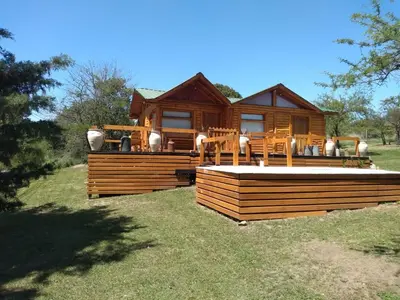 a log cabin with a deck and chairs in the yard at Talasuas -aires de montaña in Villa General Belgrano