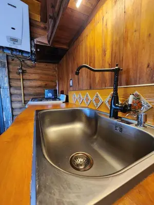 a stainless steel sink in a kitchen with wooden walls at Talasuas -aires de montaña in Villa General Belgrano