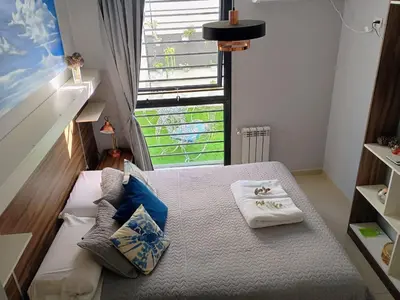 a small bedroom with a bed with pillows and a window at Depto céntrico excelente ubicación, con cochera, pileta y patio in Villa Carlos Paz