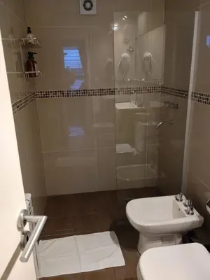 a bathroom with a shower and a toilet and a sink at Depto céntrico excelente ubicación, con cochera, pileta y patio in Villa Carlos Paz