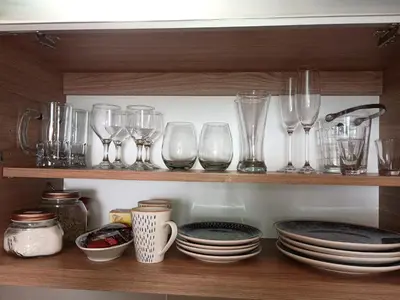 a row of glasses and plates on a shelf at Depto céntrico excelente ubicación, con cochera, pileta y patio in Villa Carlos Paz