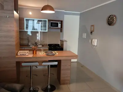 a kitchen with a wooden counter with stools at Depto céntrico excelente ubicación, con cochera, pileta y patio in Villa Carlos Paz