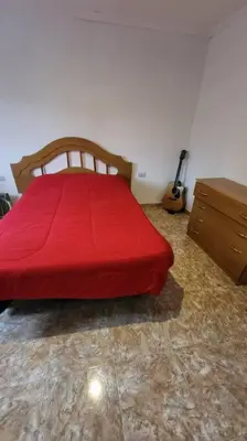 a bedroom with a red bed and a guitar at La Calera- Casa vacacional in La Calera
