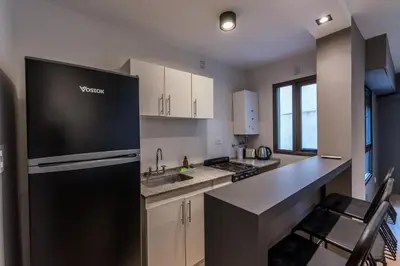 a kitchen with a black refrigerator and white cabinets at Hermoso departamento by Lofty in Cordoba