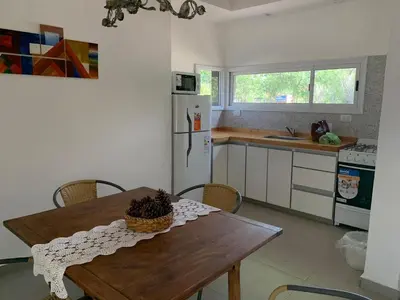 a kitchen with a table and a refrigerator and a sink at Casa Aguaribay para 4 personas, cerca del centro, Merlo San Luis in Merlo