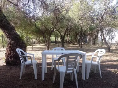 a white table and chairs sitting under a tree at Casa Aguaribay para 4 personas, cerca del centro, Merlo San Luis in Merlo