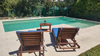 two chairs and a table next to a swimming pool at Casa con pileta en las sierras in La Calera