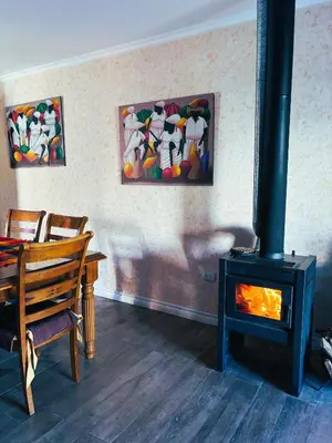 a living room with a wood stove and a table at Casa con pileta en las sierras in La Calera