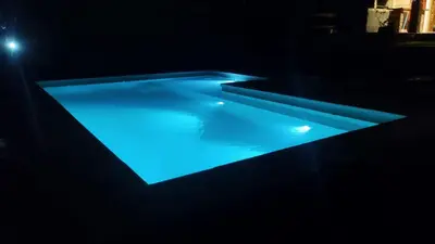 a swimming pool with blue lighting in a dark room at Casa con pileta en las sierras in La Calera
