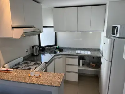 a small kitchen with white cabinets and a white refrigerator at Departamento equipado ideal para 4 en Nueva Córdoba in Cordoba