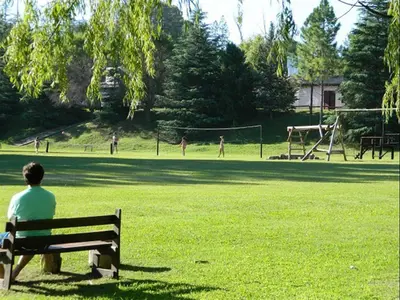 a man sitting on a bench in a park at Club Resort in Mina Clavero