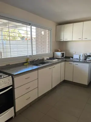 a kitchen with white cabinets and white appliances at Casa Cerro de las Rosas in Cordoba