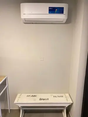 a white air conditioner hanging on a wall above a bench at Departamento -Cata- Pleno General Paz, cerca de Sanatorios, Terminal de omnibus y Nueva Cordoba, BY Apartcba in Cordoba