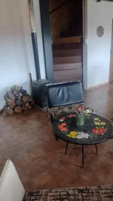 a living room with a chair and a table with flowers on it at Casa Hebe - En las sierras de Córdoba - cuenta con tres habitaciones y capacidad para 8 personas, tranquila con increibles vistas in Villa Parque Siquiman