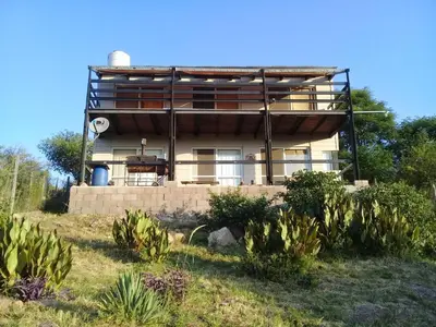 a house on a hill with plants in front of it at Casa Hebe - En las sierras de Córdoba - cuenta con tres habitaciones y capacidad para 8 personas, tranquila con increibles vistas in Villa Parque Siquiman