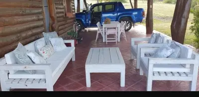 a porch with two white benches and a blue truck at Cabaña Troncos en Los Reartes in Villa General Belgrano