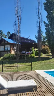 a house with a swimming pool in front of a house at Cabaña Troncos en Los Reartes in Villa General Belgrano