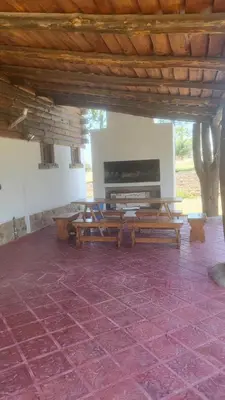 a living room with wooden tables and a fireplace at Cabaña Troncos en Los Reartes in Villa General Belgrano