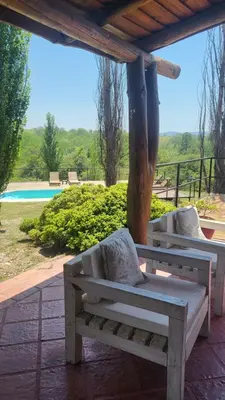 a wooden bench sitting under a pavilion near a pool at Cabaña Troncos en Los Reartes in Villa General Belgrano