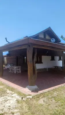 a house with a wooden roof and a patio at Cabaña Troncos en Los Reartes in Villa General Belgrano
