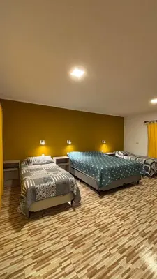 two beds in a large room with yellow walls at Cabaña Concepcion del Valle in Salsacate