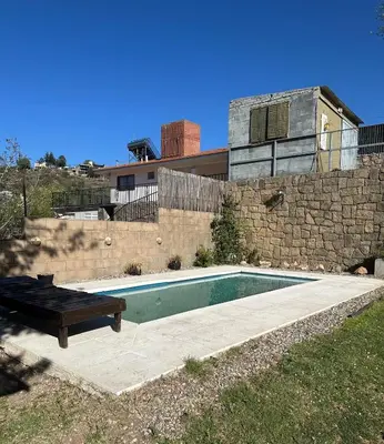 a swimming pool with a bench next to a stone wall at lahabanadepartamento in Villa Carlos Paz