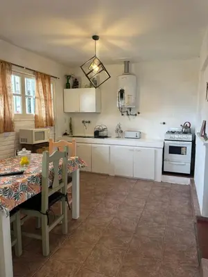 a kitchen with white cabinets and a table and a stove at lahabanadepartamento in Villa Carlos Paz