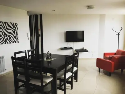 a dining room with a table and a red couch at Depto Sorrento céntrico in Villa Carlos Paz