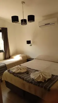 a bedroom with two beds and two lights on the wall at Ribera Sur Hotel - Los Algarrobos - Tanti in Tanti