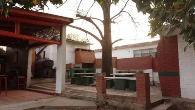 a patio with tables and a tree in front of a building at Ribera Sur Hotel - Los Algarrobos - Tanti in Tanti
